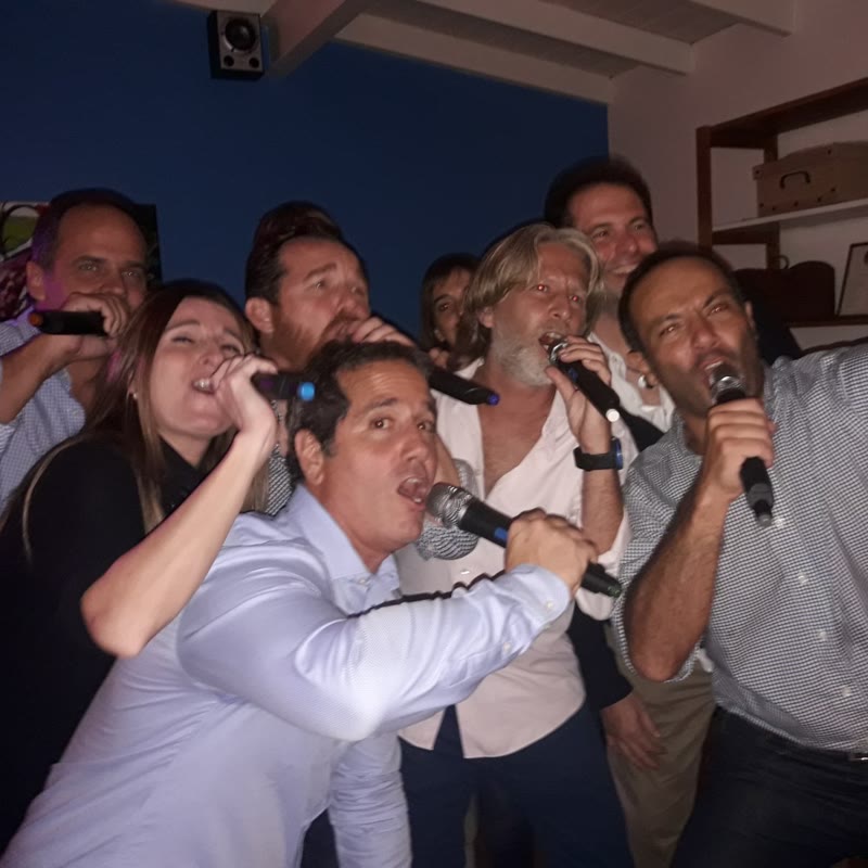 Grupo de invitados cantando juntos con micrófonos en un show de karaoke